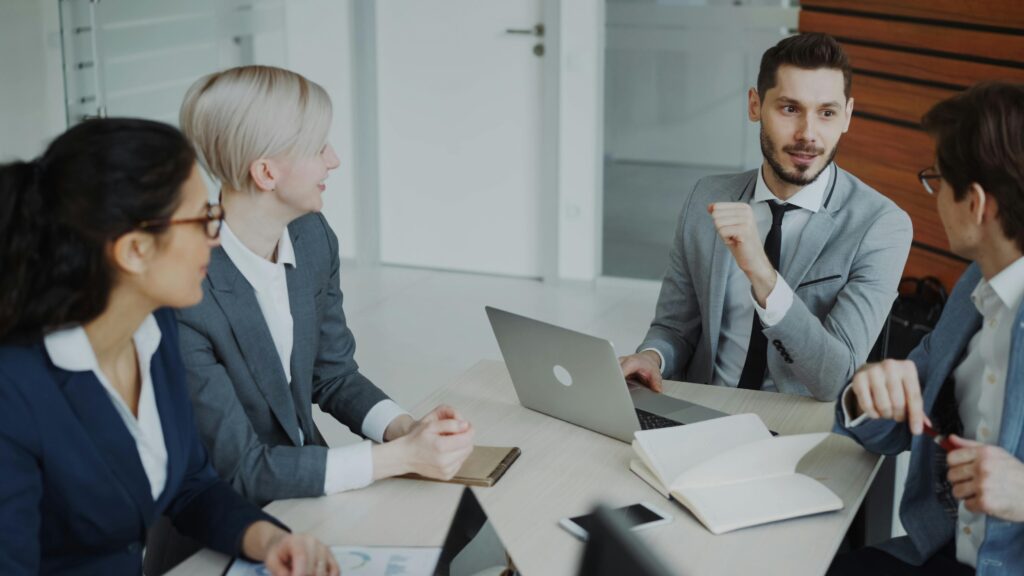 Business professionals engaged in a meeting around a conference table in a modern office space.